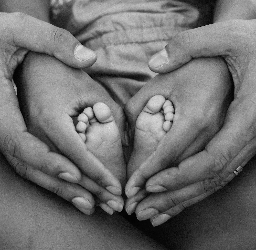 parents hands holding baby feet