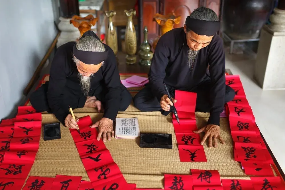two men writting on red paper