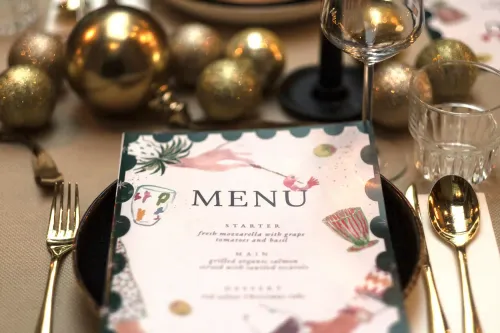 Christmas menu magazine on a plate with cutlery and flowers 